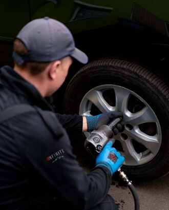 infinite autohaus man checks tire pressure using a gauge
